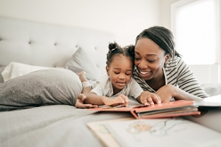 Image of mother with young girl reading on bed together